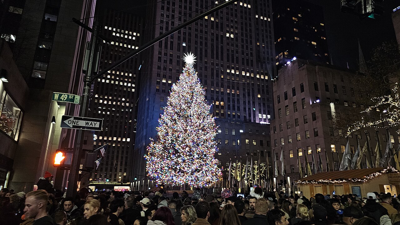 The lit Rockefeller Center Christmas tree at night above a crowd